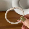 Close-up of a minimalist beige elastic hair tie with a matte cylindrical connector - Beige