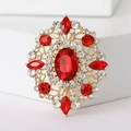 Detail of vintage gold brooch featuring red oval gemstone and sparkling crystal inlay - Red