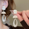 Detail of a minimalist earring made of marble resin and wood held by a hand - Off-White Resin/Wood Grain Splicing