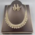 Parure de bijoux mariée avec collier strass et boucles d'oreilles sur support sombre - Doré