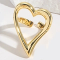 Detailopname van een gepolijste gouden hartring op een stenen ondergrond - Minimalistische Grote Hart Holle Stijl / Goud