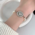 Elegant white pearl bracelet with a silver Saturn planet charm on model's wrist - 86#L0058SB (Saturn Orb Artificial Pearl Bracelet)