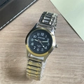 Detail view of quartz watch model 805 with silver stretch band and gold bezel on wood - Women's Watch / Two-tone Band Black Dial