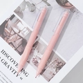 Close-up of two pink retractable gel pens on an artistic book background - Single Piece / Pink
