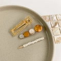Detailed view of three pearl hair clips with resin and gold leaf on a ceramic plate - Style 12 (3-Piece Set/Orange-Brown Geometric)