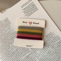 Nahaufnahme bunter elastischer Haargummis auf minimalistischem Papierkartenhalter - Stil B Mehrfarbig