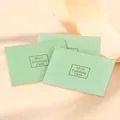 Drie lichtgroene zilverpoetsdoeken met logo op een zachte roze achtergrond voor sieraden - Zilveren poetsdoek