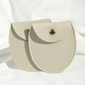 Macro shot of two round beige PU leather jewelry pouches with golden metal snap closures - 8*8.5cm / Beige