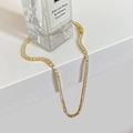 Detail van gouden tennisketting met glanzende vierkante zirkoniasteentjes op wit voetstuk - Volledige Zirkonia Ketting / Goud