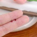 Orecchini a perno minimalisti in argento con zirconi rossi, mostrati sulla punta del dito - Griffe Verticale n. 3 / Rosso