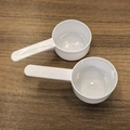 Set of 2 white plastic measuring spoons for milk powder on dark wood background - White