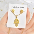 Hamsa-Hand-Schmuckset aus goldenem Edelstahl mit Halskette und Ohrringen auf Karte - Hamsa Hand