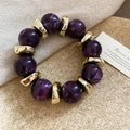 Detail van paarse marmeren acryl kralen en gouden metalen spacers op een armband - Paars-Goud