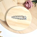 Detailed view of silver alloy hair clip with twist texture on a wooden stand - Silver Braid