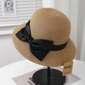Détail d'un élégant chapeau de paille avec nœud noir et étiquette anti-UV - Camel + Noeud Noir