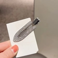 Dettaglio di un fermaglio per capelli in argento con strass lucidi su cartoncino - Argento