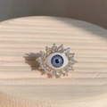 Macro detail of gold evil eye ring with blue resin iris and sparkling zircon pavé - Adjustable Open / Blue