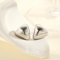 Macro shot of polished geometric triangle silver stud earrings on a textured stone base - Silver Arc Triangle