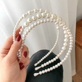 Detailed view of elegant white multi-layer pearl headband held by a hand - Style J Triple Layer Gradient Pearl Headband