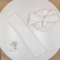 Close-up of white fabric hair bun maker with bow print detail on a ceramic plate - White