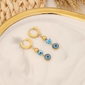 Gold evil eye hoop earrings with blue bead accents on white marble display - Gold Evil Eye Design