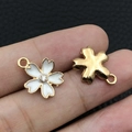 Golden flower pendants with white enamel and rhinestone inlay held on fingertips - White Enamel Rhinestone Cherry Blossom (9922)