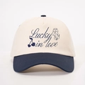 Detail of Lucky in Love embroidery on a two-tone cotton baseball cap with heart and dice - Cream/Navy Blue