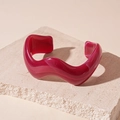 Detail view of burgundy wavy resin bangle with marble texture on stone display - Rose Red