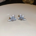 Detailed close-up of blue floral earrings with crystals on a white ceramic plate - 925 Sterling Silver Earring Post Silver Blue Flower Style