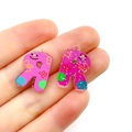 Detail shot of a pink acrylic letter R charm with floral patterns held on a finger - Letter R