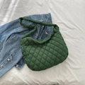 Gesteppte grüne Nylon-Tasche im Cloud-Stil auf weißem Laken neben einer Jeansjacke - Grün