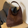 Vintage dark brown suede hobo bag with leather strap on a textured stone surface - Brown