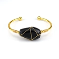 Macro detail of handmade gold wire wrapped cuff with an irregular black polished stone - Obsidian
