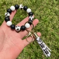Dettaglio del portachiavi a bracciale in silicone con zampe di cane e nappa stampata - Combinazione Zampa di Cane Nero Bianco (A7)