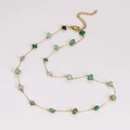 Dettaglio della collana a catena dorata con pietre verdi irregolari e chiusura a moschettone - Collana
