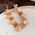 Halskette mit rosa-beigen Harzquadraten und goldenen Muschelakzenten auf Teller - Halskette / Gold & Kaffee