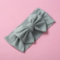 Elastic ribbed sage green baby headband with large bow detail on pink background - Light Grey Green