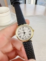 Detailed close-up of a women's quartz watch with gold case and black leather strap - Black Strap White Dial