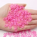 Pink bow-shaped resin beads for DIY crafts held in palm to show small scale - Rose Pink