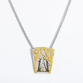 Macro view of vintage stainless steel forest necklace pendant with bird and trees - Forest