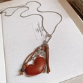 Retro long necklace with brown heart pendant, silver stars, and fringe on fabric background - Leather Heart Star Bow Ceramic Necklace