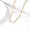 Collana con nappa dorata e maglie ovali presentata su un display geometrico bianco - Collana / Collana Oro (CDK545)