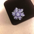 Elegant silver rotating snowflake brooch with purple zircon on a brown jewelry box - Silver Purple Brooch