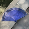Blue folding fan with intricate hollow wooden frame on stone steps for dance and decor - Hollow Feather Full Blue