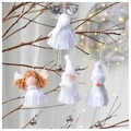 Detail of four white plush Christmas ornaments with bells hanging on rustic branches - Tassel Bell Series 4-Piece Set