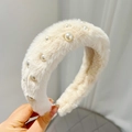 Detail of cream plush headband with pearl embellishments held against a white wall - Beige (With Pearls)