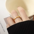 Close-up of a gold geometric fish-scale textured titanium steel ring on a finger - US 9 / Gold