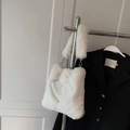 White heart-shaped plush shoulder bag with fluffy faux fur handle on display - Off White