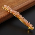 Detailed macro view of handmade wire-wrapped orange natural crystal stone hair clip - Sunstone + Gold Clip
