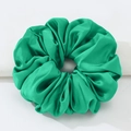 Oversized bright green satin scrunchie with pleated texture on white steps - Emerald Green